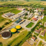 Luftaufnahme einer Biogasanlage neben Gewerbebetrieben und Feldern