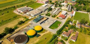 Luftaufnahme einer Biogasanlage neben Gewerbebetrieben und Feldern