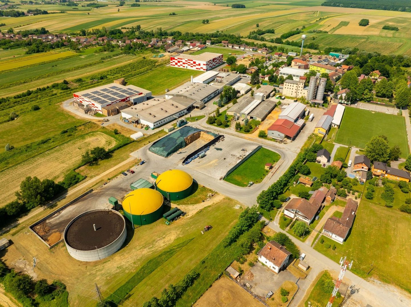 Luftaufnahme einer Biogasanlage neben Gewerbebetrieben und Feldern
