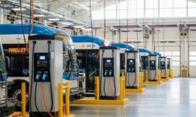 Elektrobusse stehen an mehreren Ladestationen in einer Busgarage