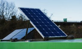Solarmodule auf einem grünen Fahrzeugdach vor einer Straßenbrücke