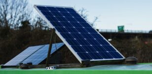 Solarmodule auf einem grünen Fahrzeugdach vor einer Straßenbrücke